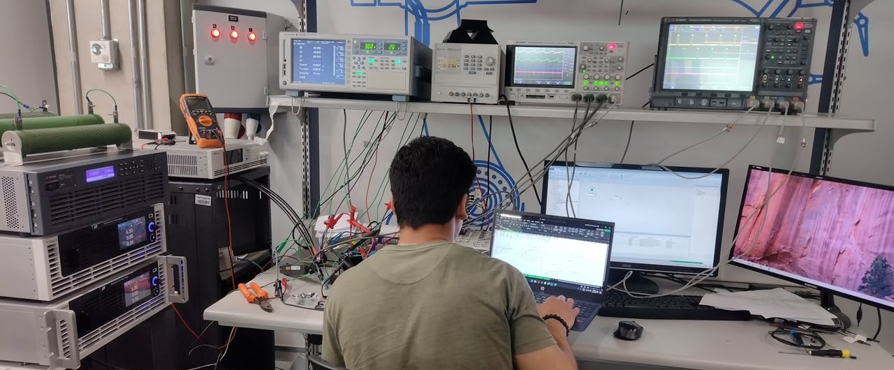 Engineer recording converter measurements at a bench with programmable sources, a power analyser and oscilloscopes