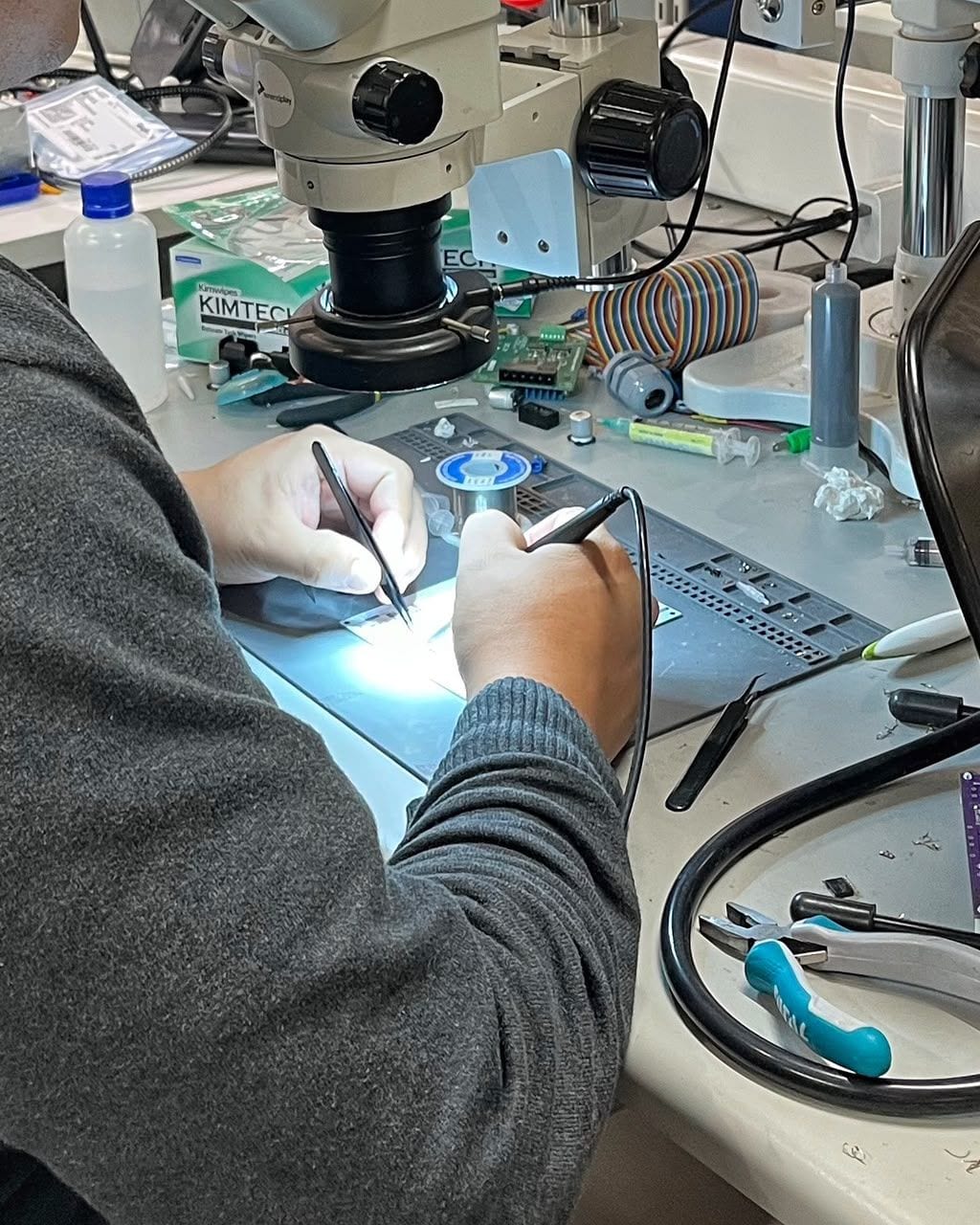 Hand soldering a board under a stereo microscope